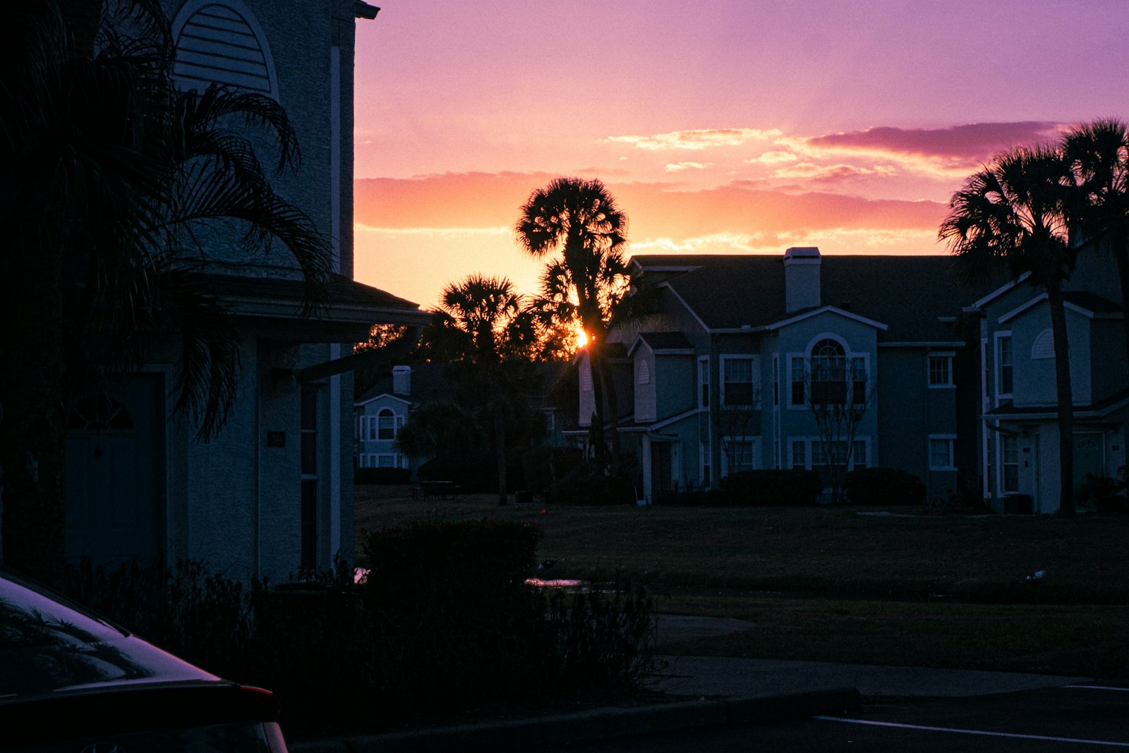 Apartment buildings silhouetted against a vibrant sunset sky.
